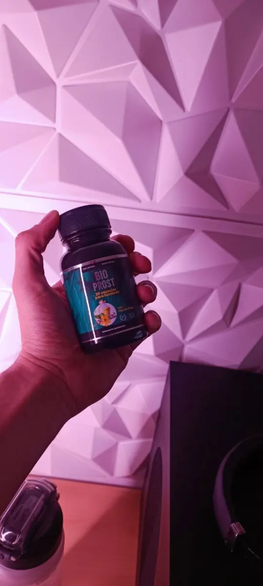 Frasco de Bio Prost en una mano frente a una pared de paneles